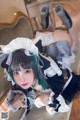 A woman in a maid outfit sitting on a chair.