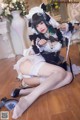 A woman in a maid outfit is sitting on the floor.