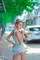 A woman in a white tank top and denim shorts holding a drink.