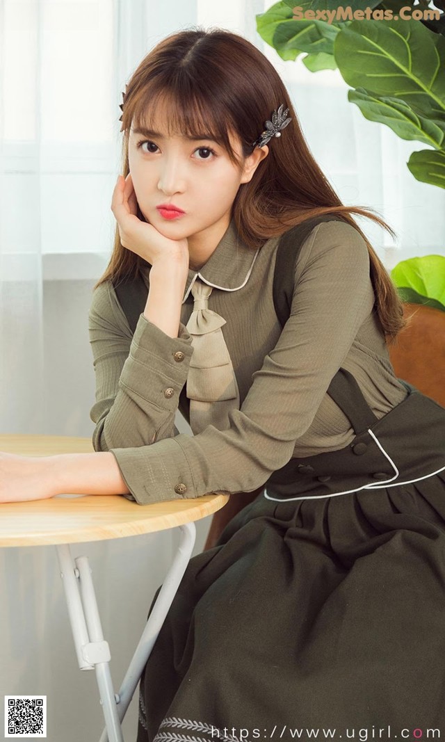 a woman sitting at a table with her hand on her chin