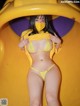 A woman in a yellow bikini is posing on a yellow slide.