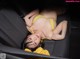 A woman in a yellow bikini laying in the back seat of a car.