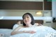 A woman laying on top of a bed covered in white sheets.