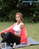 A woman sitting on a yoga mat in the grass.