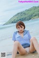 A woman in a school uniform sitting on the beach.