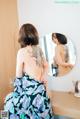 A woman with a tattoo on her back is looking at herself in the mirror.