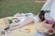 A woman laying on a picnic blanket in the grass.