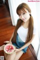 A woman sitting on the floor eating a slice of watermelon.