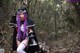 A woman with purple hair is posing in the woods.