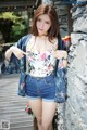 A woman in a floral top and denim shorts posing for a picture.