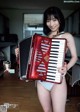 A woman in a white underwear holding an accordion.