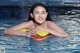 A woman in a swimming pool holding an inflatable toy.