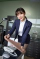 A woman in a business suit standing next to a desk.