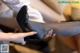 A woman is putting on a pair of black high heels.