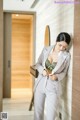 A woman in a gray suit leaning against a wall.