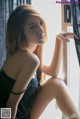 A woman sitting on a window sill looking out the window.