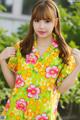 A woman in a yellow and pink floral shirt posing for a picture.