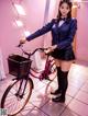 A woman in a school uniform standing next to a bike.