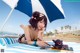 A woman laying on a beach under an umbrella.