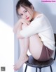 A woman sitting on top of a stool with her legs crossed.