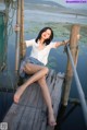 A woman sitting on a wooden dock by the water.