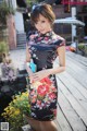 A woman in a black and red floral dress posing for a picture.