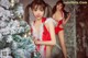 A woman in a red lingerie standing next to a Christmas tree.