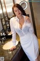 a woman in a white dress standing in front of a sink